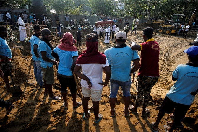 Gravediggers watch the arrival of a coffin to a mass burial site during a funeral, days after a string of suicide bomb attacks on churches and luxury hotels across the island on Easter Sunday, in Negombo